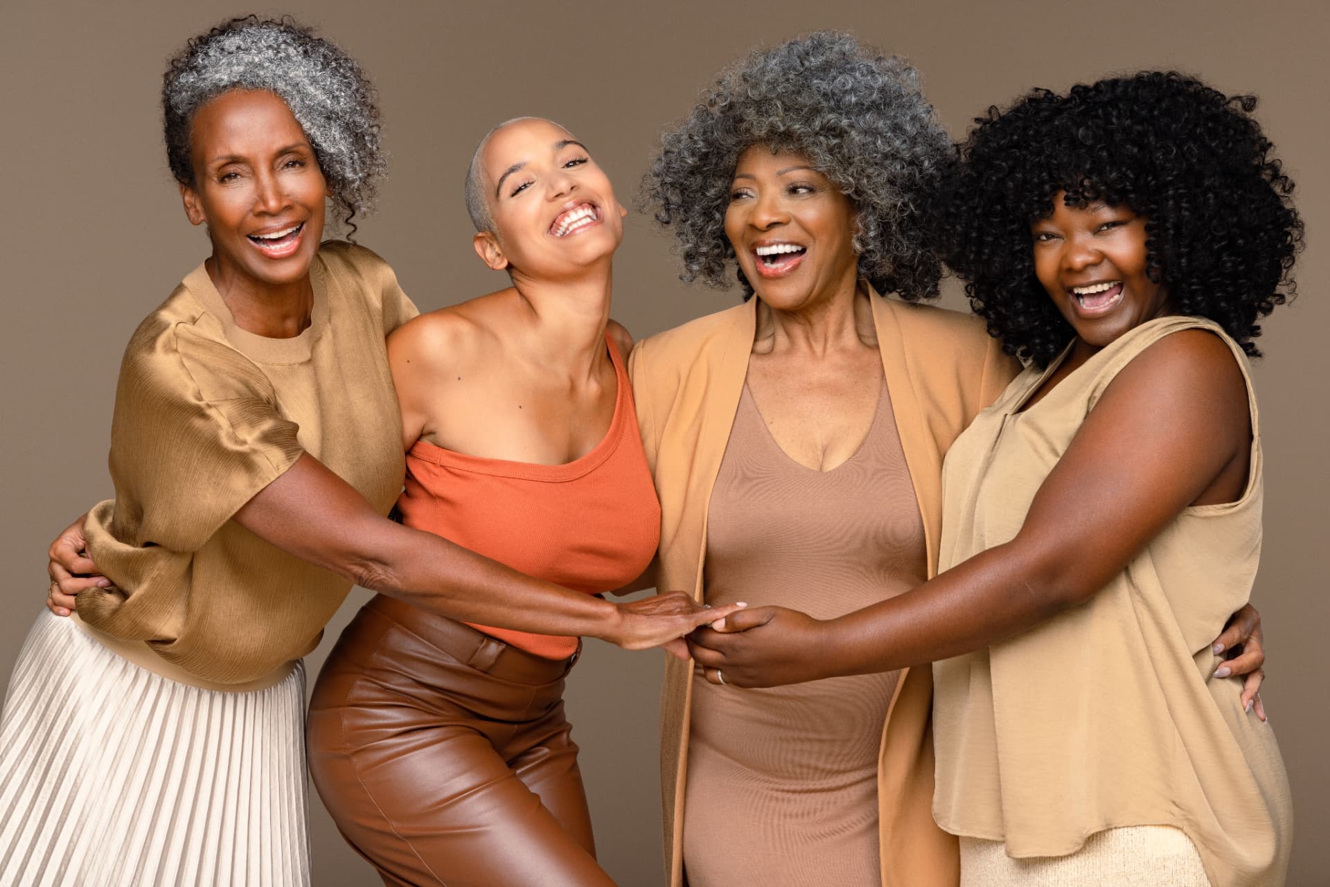 Four Black women of different ages laughing and embracing together